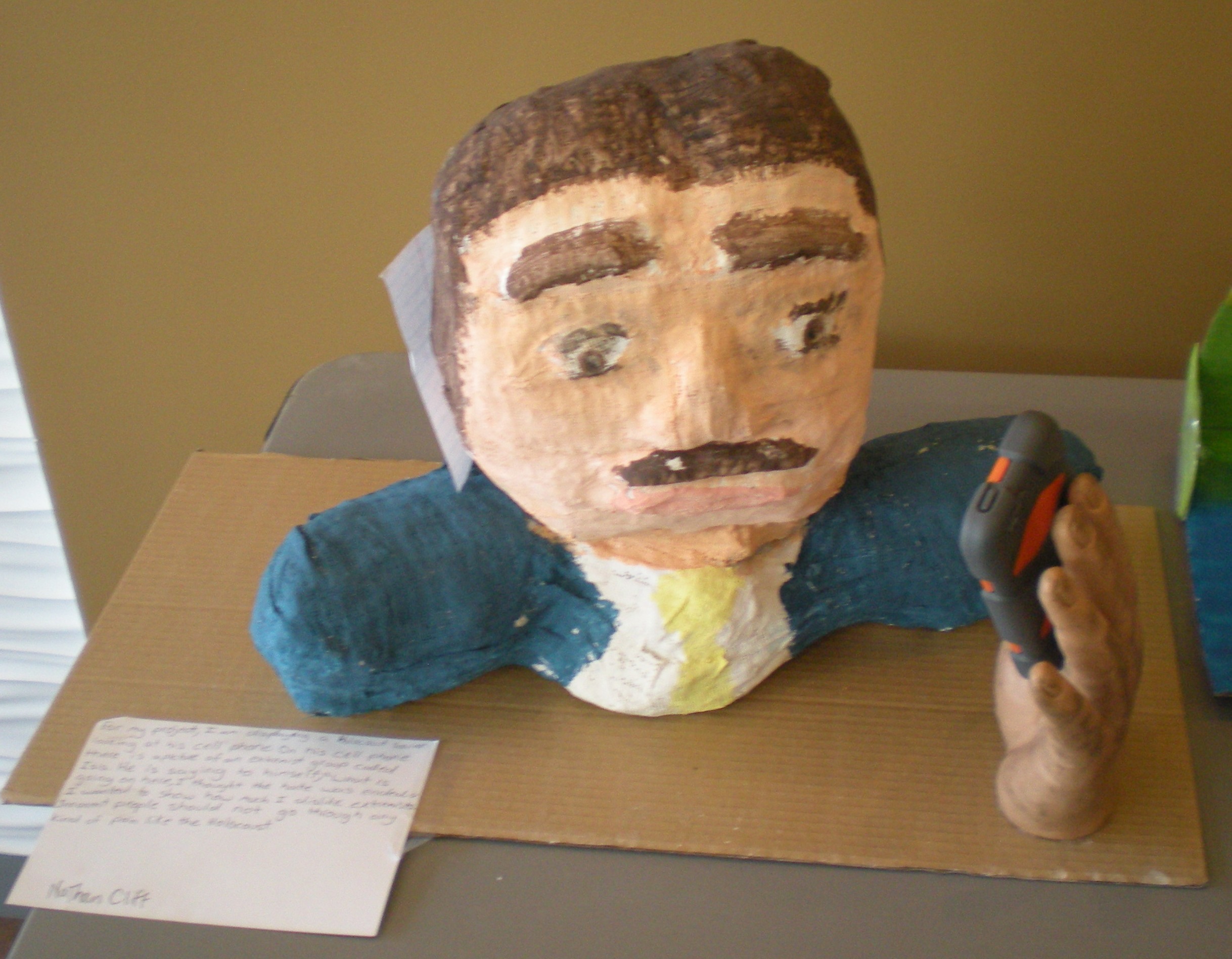 A paper cache head holding a cell phone. 